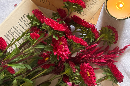 ガラスの花びんに活けられたワインレッド色のトルコキキョウ。白のクラシックな置時計。