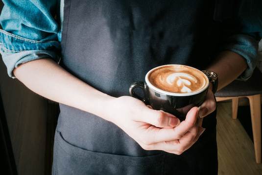 エプロンをつけたカフェの正社員とパート店員。横一列に4人並んで立っている。