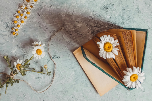 デスクに広げられたリングノート、ボールペン、タブレットケース。ガラスの小瓶に飾られたガーベラの花。