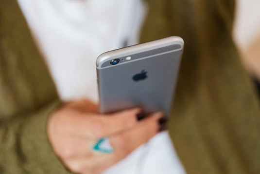 スマートフォンを操作するビジネスウーマン。水色のシャツ姿。