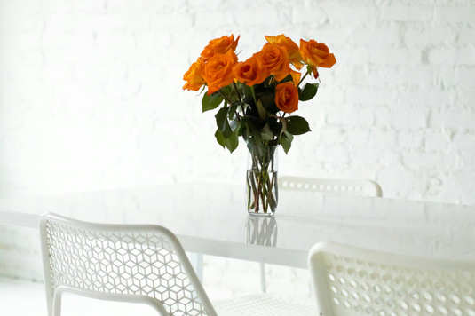 オフィスの打ち合わせテーブル。オレンジ色のバラの花が飾られたガラスの花瓶。