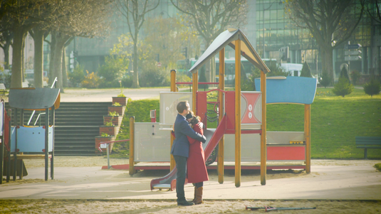 Rencontre romantique dans une publicité : deux amoureux devant un parc pour enfants