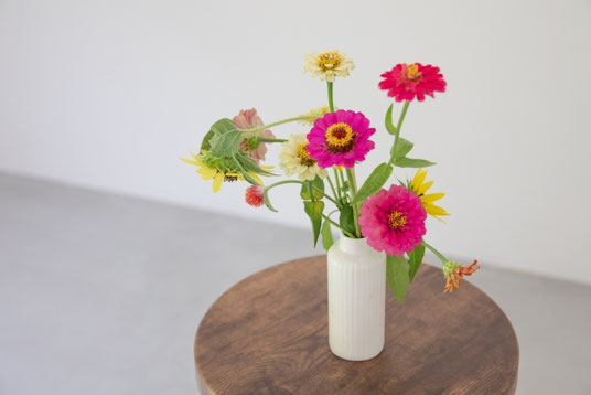 木製のスツールの上に飾られた花瓶。ガーベラの花。