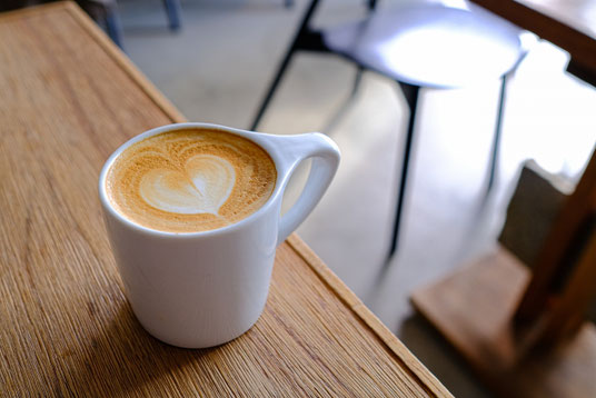 カフェの店内。テーブルに置かれたコーヒーのマグカップ。