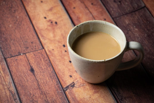 木製のテーブルに置かれたカフェオレのマグカップ。