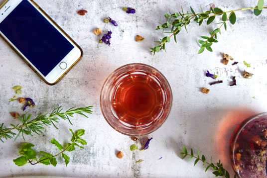 紅茶のカップとスマートフォン。ポプリが飾られたガラスの鉢。ハーブ。