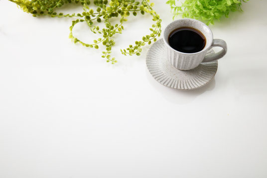 コーヒーの入ったカップ&ソーサ。傍らにグリーンのつる。