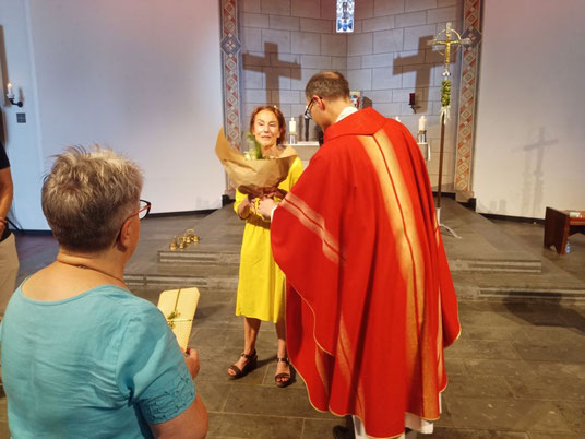 Das Foto zeigt, wie Pfarrer Holger Schmitz die langjährige Pfarrsekretärin Monika Euteneuer auf den Stufen des Altars in den Ruhestand verabschiedet.