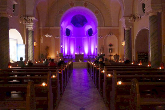 Das Foto zeigt eine mit Kerzenlicht und blauen Strahlern stimmungsvoll beleuchtete Kirche zum Rorategottesdienst