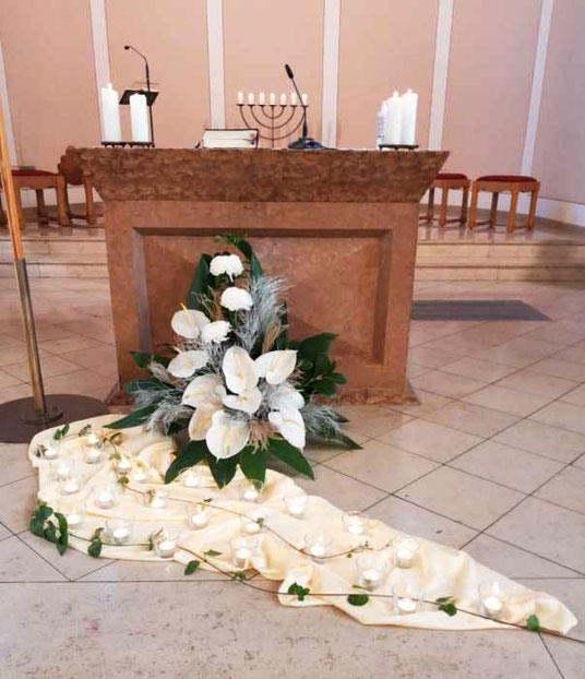 24 Kerzen am Fuß des Altares für 24 im zurückliegenden Jahr verstorbene Gemeindemitglieder