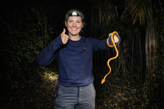 Traveler holding a small Amazon snake during a guided jungle night excursion in Peru
