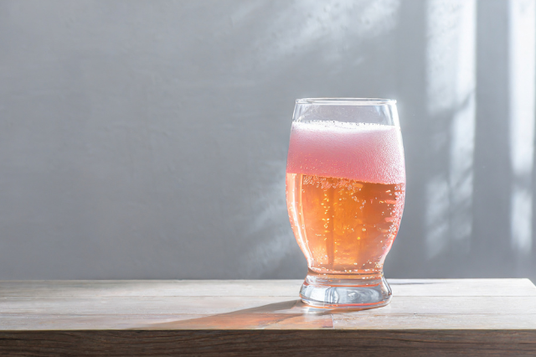 夕方のオフィスのテーブルに置かれたノンアルコール飲料のグラス。