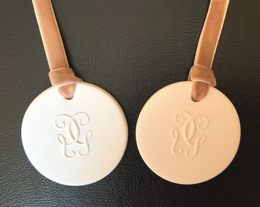 GUERLAIN - 2 CERAMIQUES AVEC LE LOGO GUERLAIN, MONTEES SUR RUBAN DE VELOURS