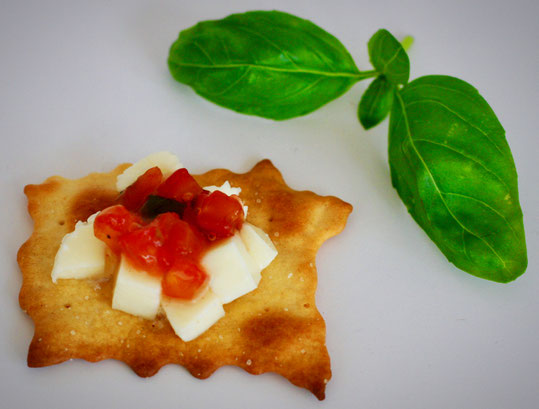 Cracker mit Mozzarella Würfel und Tomaten Basilikum Relish