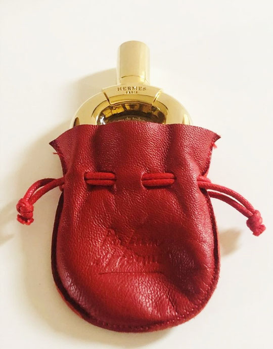 HERMES - PARFUM D'HERMES EAU DE TOILETTE : FLACON METAL DORE PRESENTE DANS POCHON CUIR ROUGE