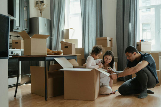 Vater, Mutter und Tochter zwischen Kartons in der neuen Küche