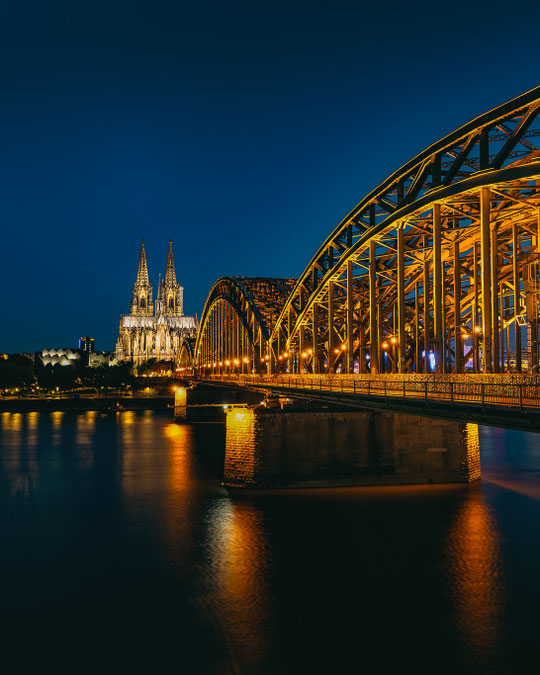 Die goldene Hohenzollernbrücke in Köln mit Dom in der blauen Stunde (Architekturfotografie)