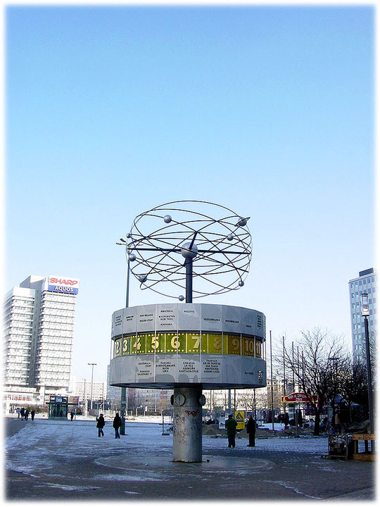 Ein Bild von der DDR Weltzeituhr am Alexanderplatz in Berlin Mitte. Das Foto ist aus dem Jahr 2006 und man sieht noch deutlich die Begrünung des Alexanderplatzes im Hintergrund.
