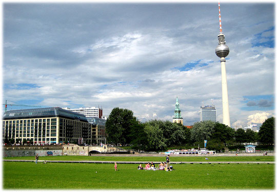 Ein Foto von der Wiese, auf der früher der Palast der Republik stand. Auf dem Foto ist im Hintergrund der Fernsehturm zu sehen, daneben das Park Inn Hotel am Alexanderplatz und die Marienkirche.