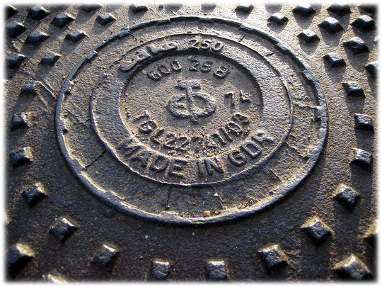 Bild von einem Straßendeckel in Berlin. Made in GDR. Ein Symbol der DDR auf einem Kanaldeckel in den Straßen von Ostberlin. Fotos von einem Gulli