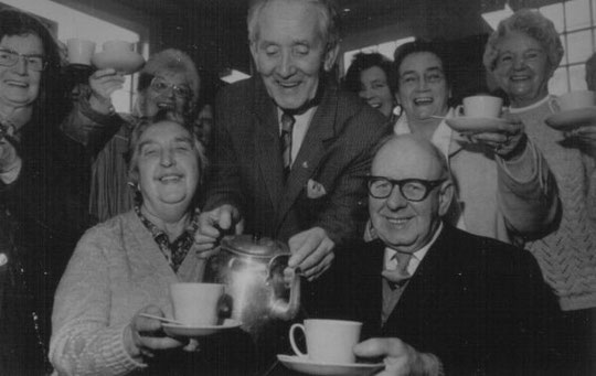 The 100,000th cup is celebrated, February 1987. In the centre is Arthur Williams, leading light of the Coffee Morning, and the couple in front are Miriam and Frederick Bates.