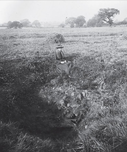 A lady sits by a bomb crater at Lakey Lane, caused by a Zeppelin raid