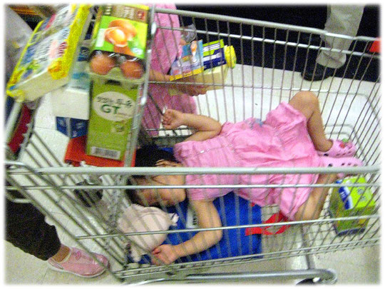 Pictures of a cute Korean child sleeping in a supermarket cart trolley. Bilder von einem koreanischen Kind das in einem Einkaufswagen für Lebensmittel und Essen schläft. Bild aus Südkorea.