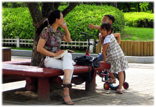 This photo shows a mother using her telephone and her two children play aside. They love Seoul like me! Bilder von spielenden Kindern und ihrer Mutter die gerade telefoniert.