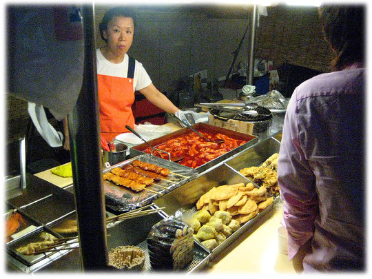 This photo shows a typical korean street food snack. Picture of a Korean cooking woman. Bilder von einer koreanischen Frau die einen Straßenimbiss betreibt und gerade kocht.