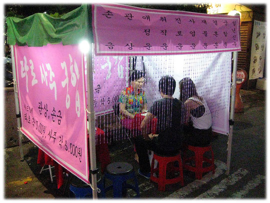 Pictures of a street fortune teller. The woman can predict the future....maybe! Many fortune tellers sit in a small tent on the street in Korea. Die Fotos zeigen junge Koreaner bei einem Wahrsager