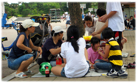 Photos of a family with many children having a picnic at Han River park (Yeouido park). Bild von einer Familie mit Kindern die in einem Park spielen und Picknick machen.