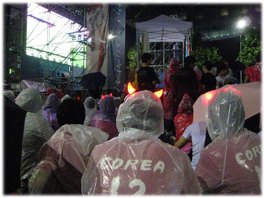 Picture of the Koreans wearing a dress which looks like the red devils korean soccer team. It's interesting for american and german tourists to watch the public viewing. Bild Fussball für Touristen.
