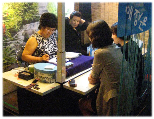 On this picture you see a street fortune teller giving advice to two young women. They ask about their future with their love. Bilder über ein Liebespaar beim Wahrsager in der Straße