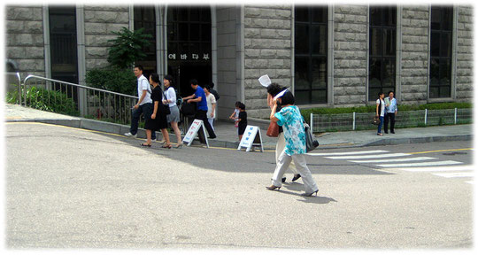 This picture shows two young Korean women walking in the city sunshine. They protect face with paper to avoid getting tanned. The image was taken right after church service. Bild von Frauen aus Korea