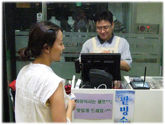 This picture shows a woman who pays the bill at the restaurant check out cash desk. Das Bild zeigt eine junge Koreanerin die das Essen im Gasthaus bezahlt