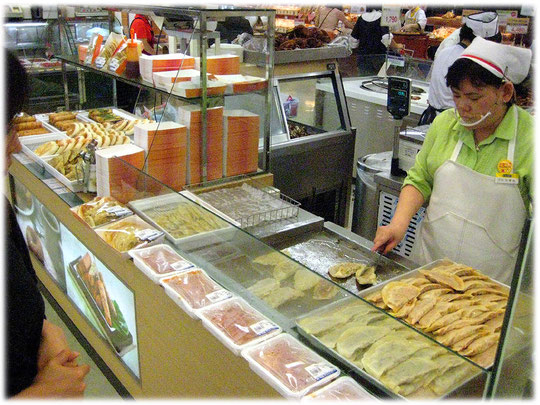 Picture of a Korean woman making some food for the shoppers and customers of the South Korean food market. Bild einer Frau die asiatisch koreanisches Essen und Gerichte vorbereitet.