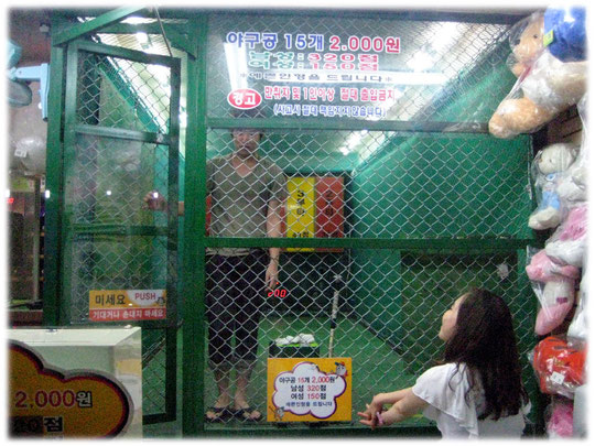Pictures about a young man who is playing indoor baseball at a amusement shop at Gangnam area, Seoul. A young woman is watching him. Fotos von einem Koreaner in Südkorea