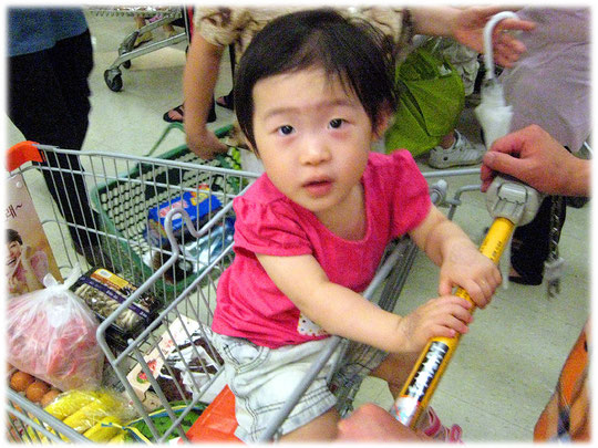 Photo of a small Korean boy sitting in the shopping cart at a South Korean shopping market. Foto eines koreanischen Kindes in einem Supermarkt Einkaufswagen. 