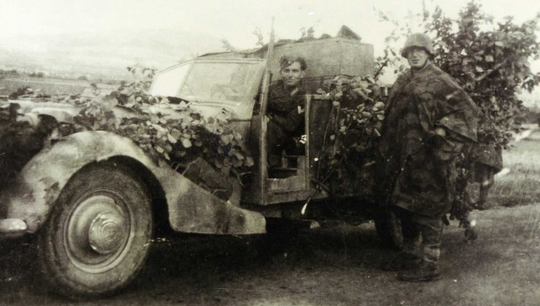 Lieutenant Lacoste debout près du véhicule dans le Cantal été 1944.