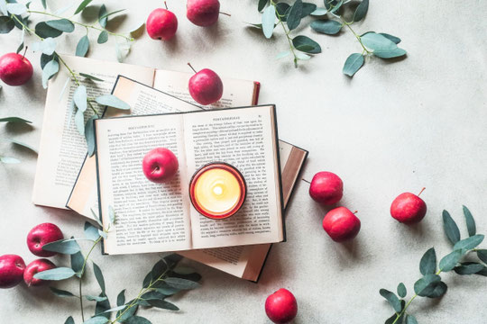 ページが開かれた赤の表紙の洋書。そのうえに置かれた紅茶のティーカップ。ラベンダーの花。
