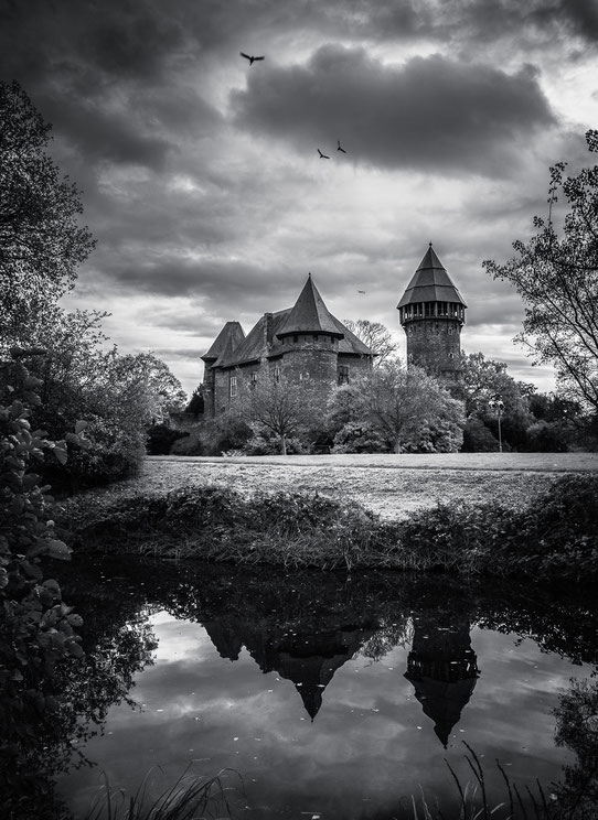 Schwarz-weiß Foto vom Mittelalterlichen Wasserschloss Burg Linn in Krefeld mit Spiegelung im Burgraben