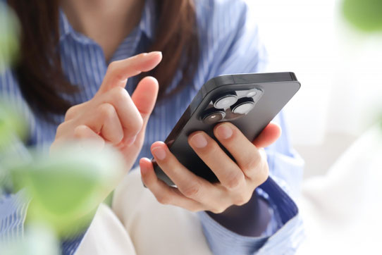 ベッドでスマホを操作する女性。