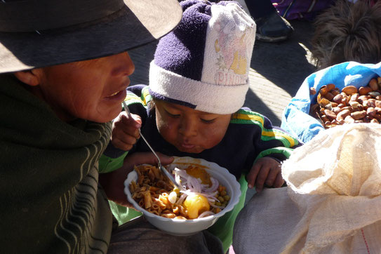 Het straatbeeld op een lokale markt. De kinderen eten mee bij moeder op straat . Het contrast met "onze wereld" is dan ineens weer erg groot.