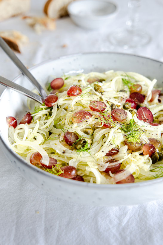 Frischer Fenchelsalat mit süßen Weintrauben, Kapern und Honig-Balsamico-Dressing auf rustikalem Teller serviert – leichtes Herbstgericht.