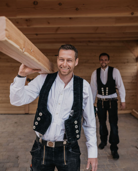 Lächelnde Zimmerer unter einem Carport aus Holz