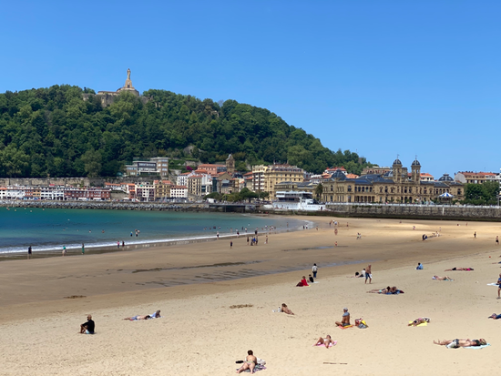la spiaggia di San Sebastian con la città vecchia nello sfondo e la gente che prende il sole in spiaggia