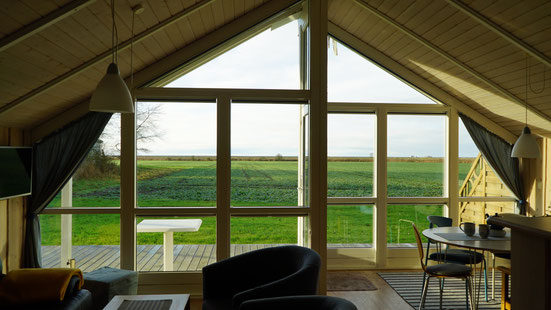 Große Fensterfront mit Blick auf ein weites, grünes Feld.