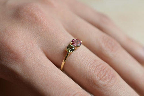 bague de fiançailles en or jaune recyclé sertie de deux tourmalines verte et rose portée sur la main d'une future mariée