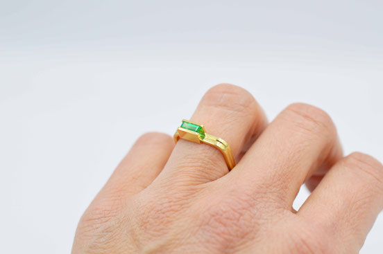 Bague en or jaune 18 carats recyclé sertie d'une émeraude portée sur main de femme