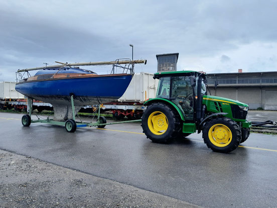 Ein Traktor von Gerster Recycling steht auf einem Industriegelände. Ist ein Schiff zur Entsorgung zu sehen. Das Bild zeigt einen Recycling- und Abfallentsorgungsbetrieb.
